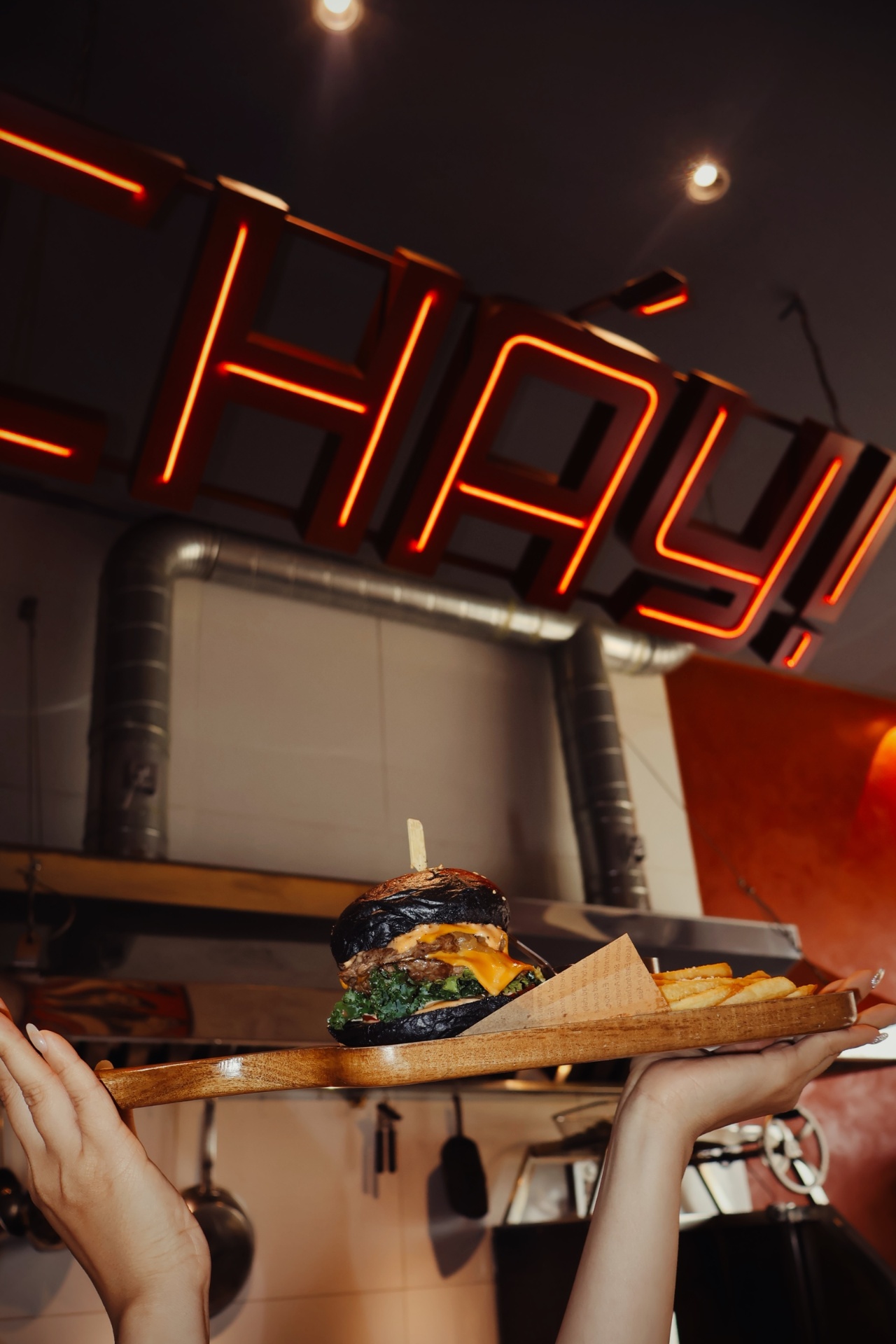 Cháy! burger and fries on tray under neon sign